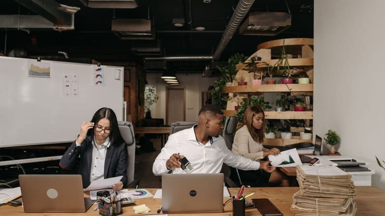 Three colleagues working at laptops in a shared office
