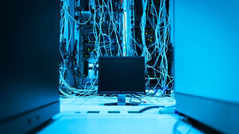A monitor among cabling and equipment racks in a server room